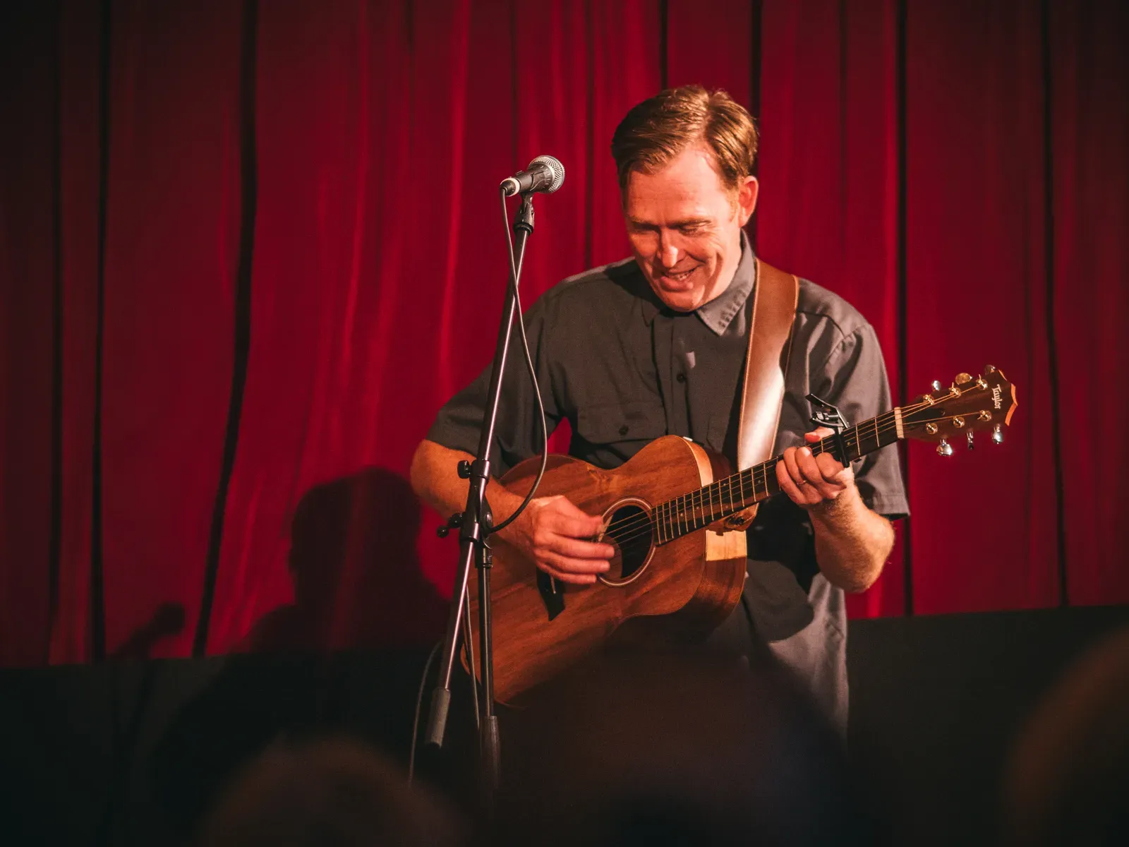 Andy blickt mit einem freudigen Lächeln auf seine Gitarre